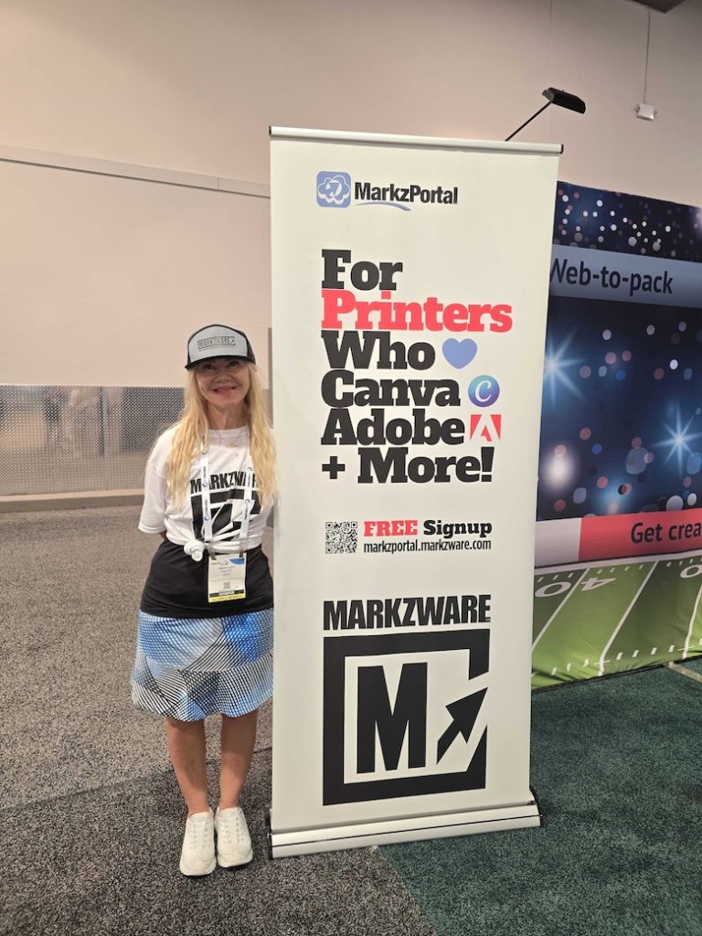 DRUCK United Expo 2024: Mary Gay Marchese Pettit, MarkzPortal für Drucker, die lieben CanvaAdobe + mehr. Markzware (780x1040): Mary Gay Marchese-Pettit steht bei Markzware's Display Poster, das die MarkzPortal Logo über „Für Drucker, die lieben Canva, Adobe + Mehr-Text, ein QR-Code, „KOSTENLOSE Anmeldung markzportal.markzware.com“-Text, MARKZWARE in schwarzer Schrift über dem Markzware „M“-Logo.